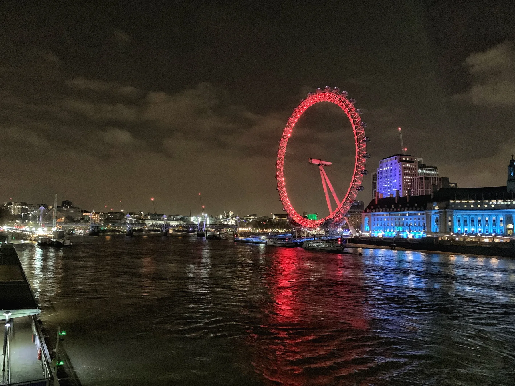 The London Eye glowing above the black water of the Thames.
