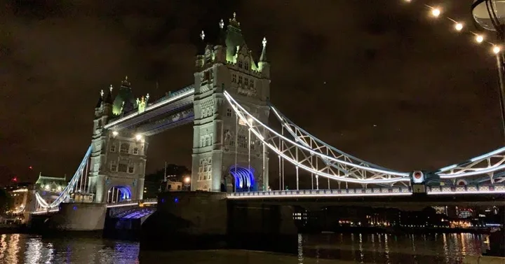 Tower Bridge lit up blue across the river at night.