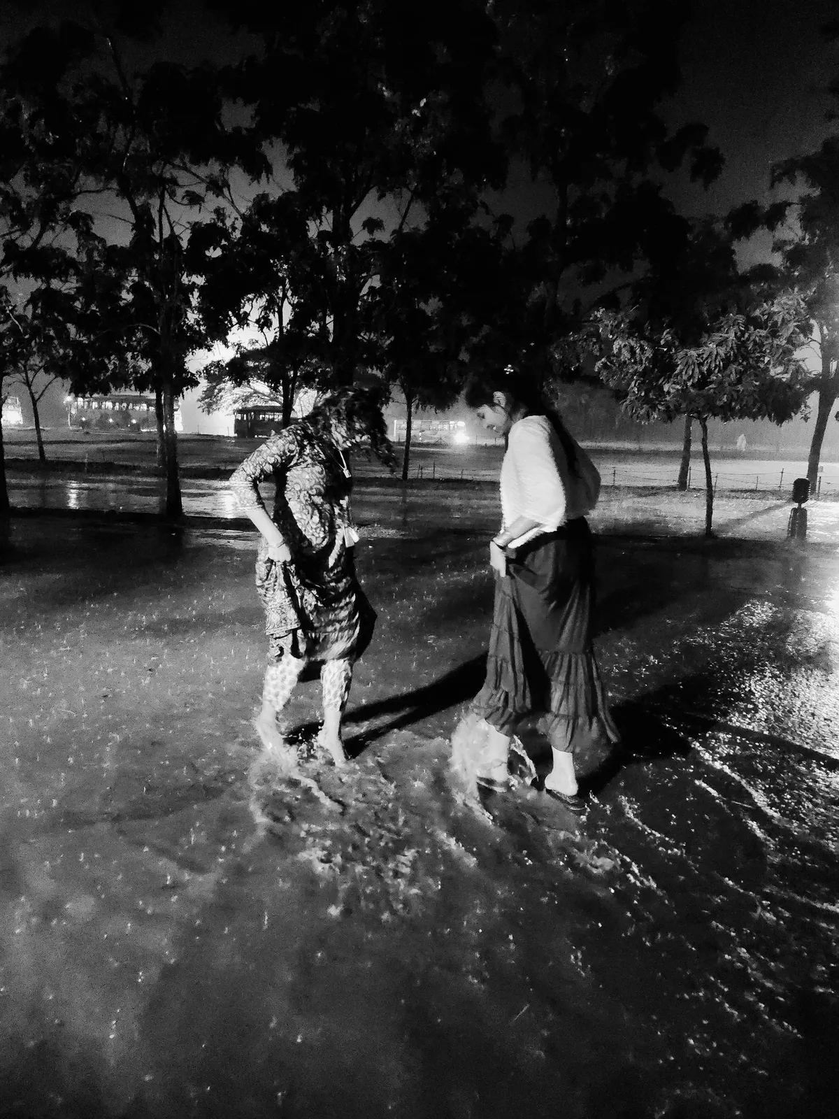 Two people standing ankle-deep in a flooded street at night, in the rain.