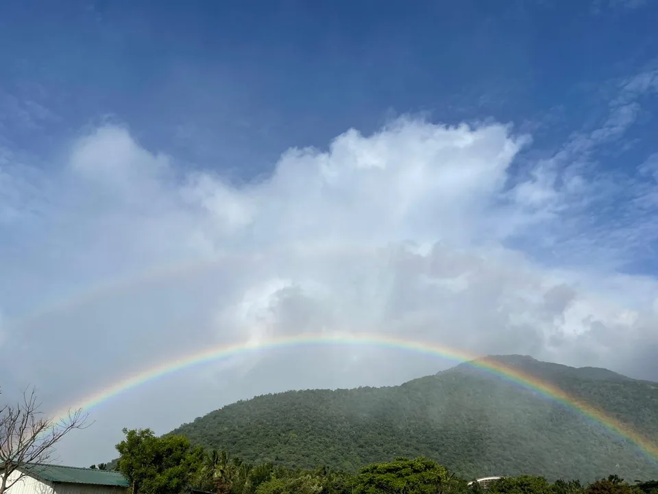 A double rainbow arching over green hills after rain.