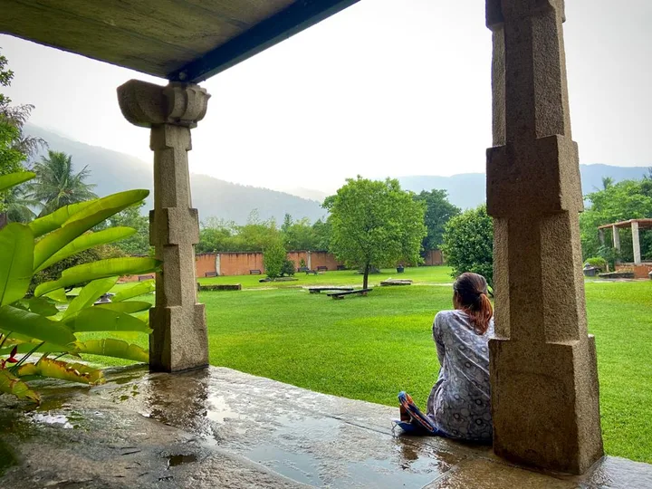Stone columns opening onto a wide green lawn after rain.