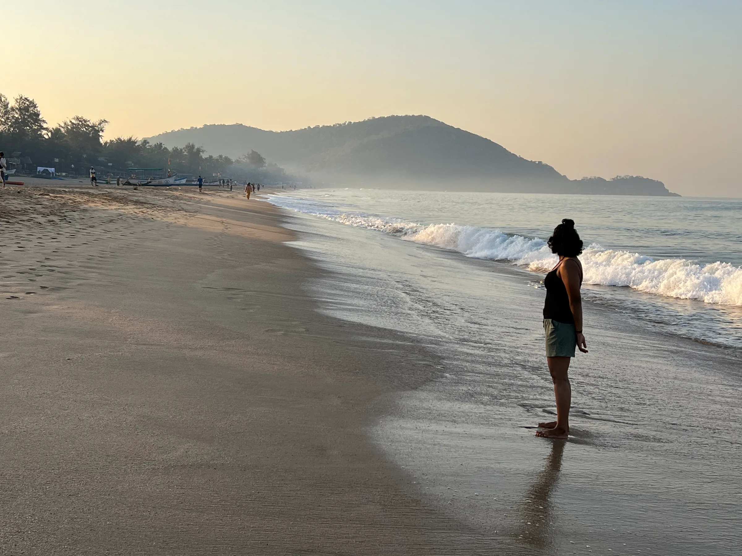 A misty beach at dawn, a headland in the distance.