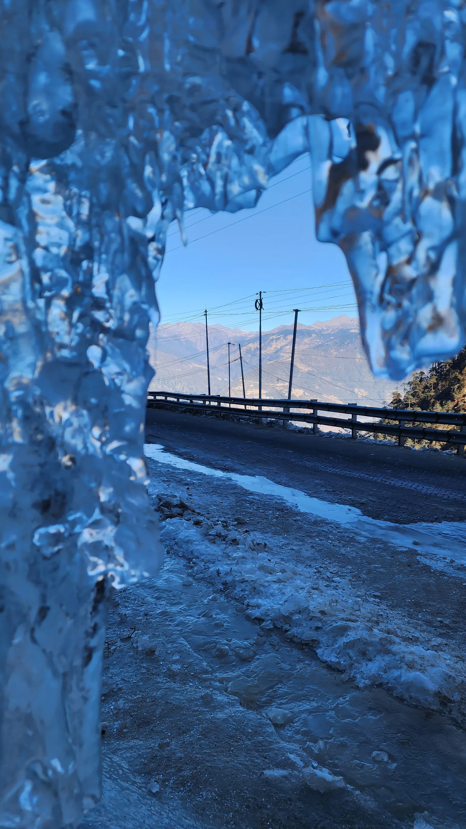 A wall of icicles hanging beside a frozen mountain road.