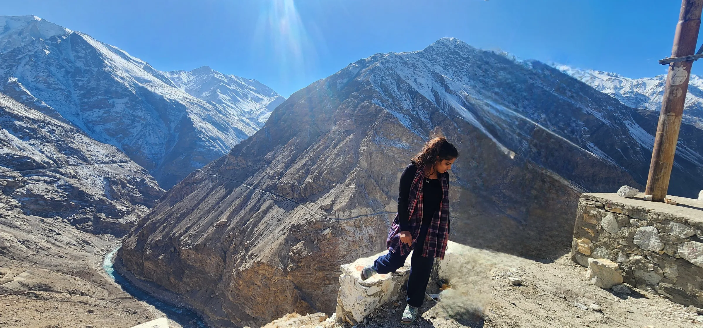 A river gorge folding away below snow peaks, a small figure on the rim.